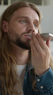 Positive talking Caucasian man male student guy recording voice mail with modern mobile phone technology easy command talk to smartphone usage online assistant app sending audio message in university