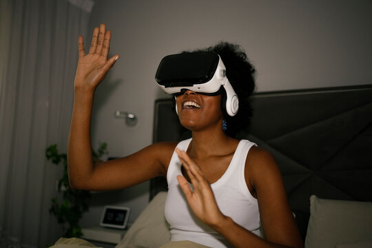Woman using VR glasses in bed during evening leisure time