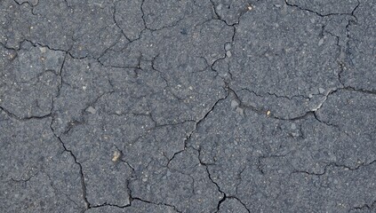 Obraz premium Severely damaged grey roadway. Bird's-eye perspective reveals coarse texture and cracks