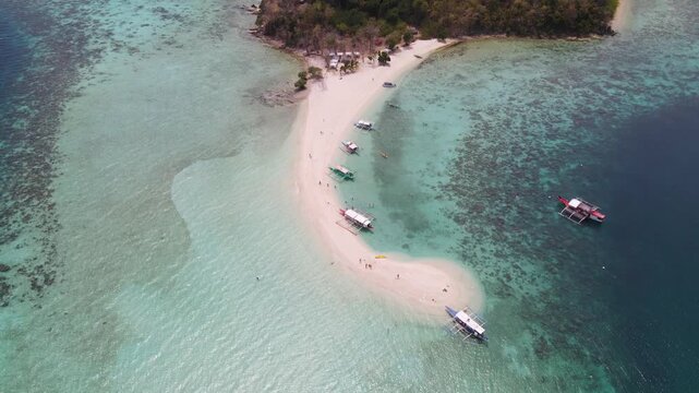 Aerial view of boats docked on a pristine white sand beach surrounded by turquoise waters, a tropical island paradise, Coron, Mimaropa, Philippines.
