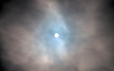 A dramatic sky with thick clouds partially covering the sun