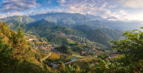 Panoramic view on serene morning hills with clouds illuminated by soft sunlight in village near in popular tourist destination of Sapa, North Vietnam.