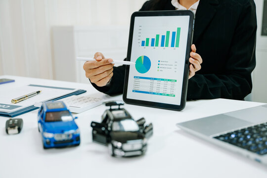 Businesswoman presenting auto insurance sales data and financial analysis on tablet with car models, investment, marketing strategy and dealership concept.