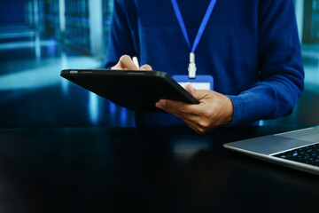 Naklejka premium Technology professional using stylus on laptop in data center. Concept of cybersecurity, programming, cloud computing, digital business, innovation