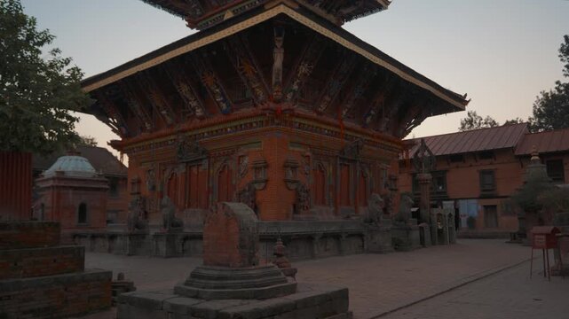 Exterior view of Changu Narayan Temple, Nepal. Ornate woodwork and golden elements at sunset.