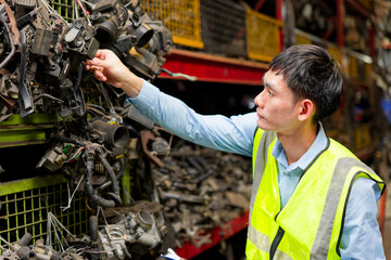 Worker examines a pile of metallic parts and debris in the factory