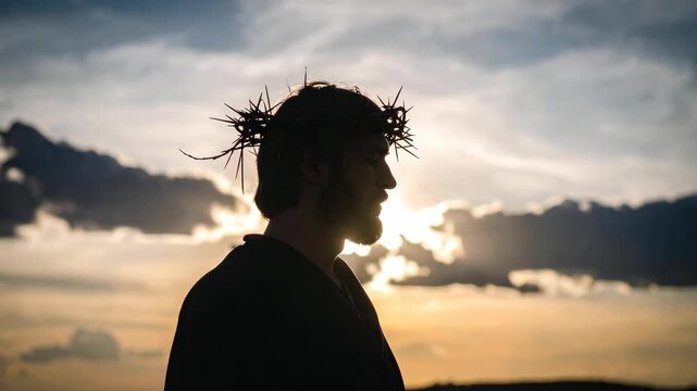 Silhouette of a man with a crown of thorns against a dramatic sunset sky