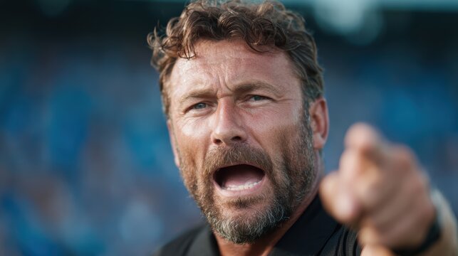 A coach passionately gestures and communicates with players on the field, exuding intensity and determination during an important match moment, capturing vital teamwork spirit.