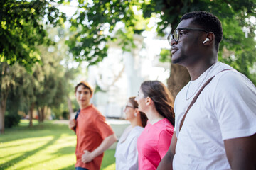Naklejka premium Group of diverse friends walking together in a sunlit park, enjoying nature and each other's company, showcasing friendship and outdoor leisure activities
