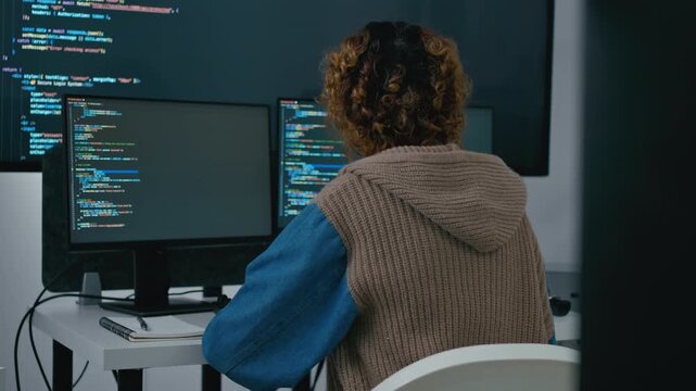 software engineers woman and AI developers working on programming code on computer screens in a dark office. Concept of machine learning, digital transformation, and future technology.