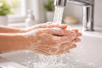 Fototapeta premium Close-up of hands washing with soap under running water