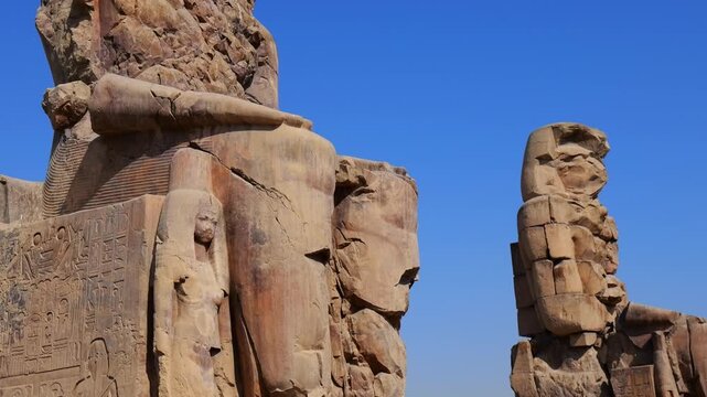 Colossi of Memnon twin guardians at mortuary temple entrance in Luxor Egypt, massive weathered statues of Amenhotep III