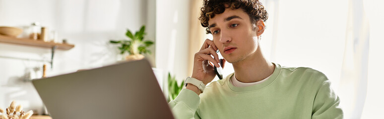 Handsome young man in a pastel green sweatshirt working in a bright modern apartment
