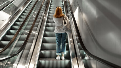Woman walking up escalator in shopping center during busy afternoon hours