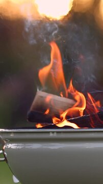Bright flames in a BBQ grill with a blurry rural village background. Vertical 