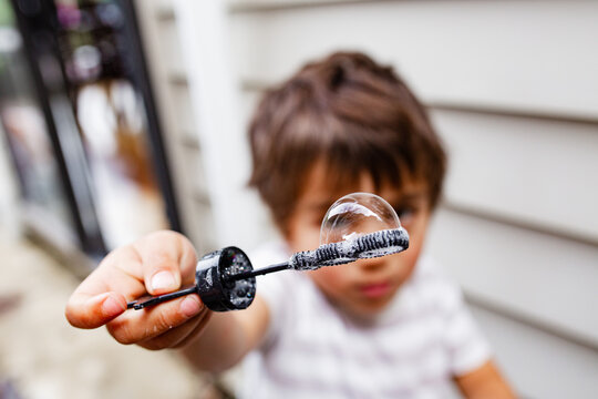 Young boy blowing bubbles with a bubble wand