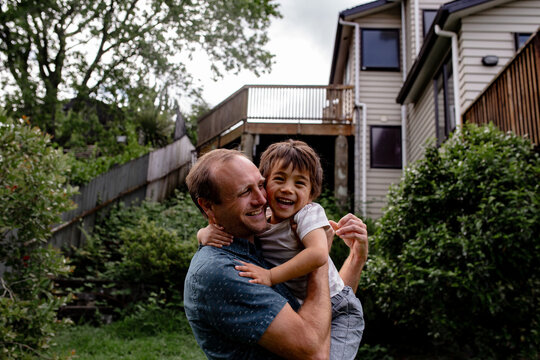 Kiwi father carrying son in the backyard