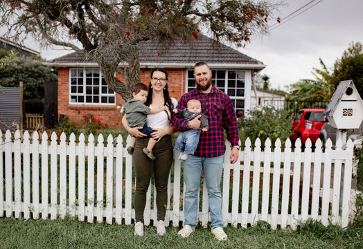 Happy family standing in front of white picket fence