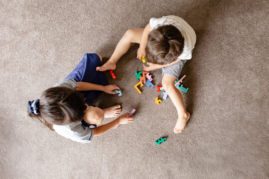 Two kids playing with colourful blocks on carpeted floor
