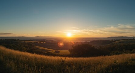 Obraz premium Warm sunset tones highlighting a vast countryside with hills