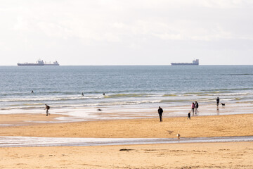 Atlantic beach with surfers and ships on horizon in Cascais