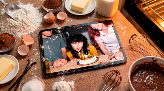 Still life of cake ingredients with final result on digital tablet during birthday candle blowing moment