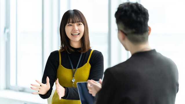 打ち合わせで会話する女性社員と男性社員, Business colleagues talking during meeting in office