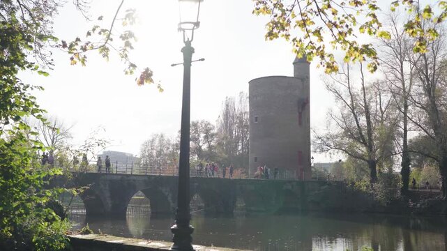 Bridge with castle tower reveal from park bench in Bruges Belgium