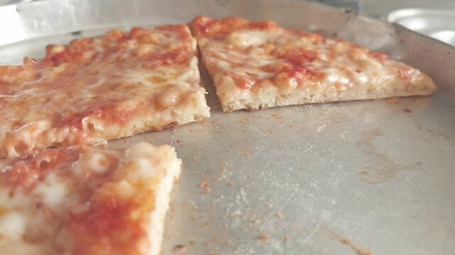 Rotating close-up of sliced margherita pizza pieces with tomato and mozzarella.