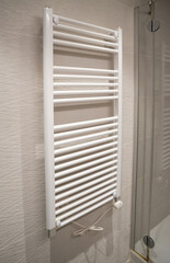 White electric towel warmer wall mounted in a modern bathroom, providing warm towels and heating for comfort and luxury living