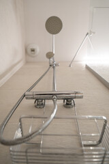 Chrome shower system with mixer tap, flexible hose, rain showerhead and empty wire soap dish in a bright, modern bathroom for clean, contemporary daily hygiene