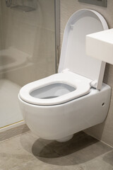 White ceramic wall-mounted toilet with an open lid in a modern bathroom, emphasizing cleanliness, hygiene, and contemporary interior design elements