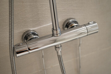 Chrome shower mixer tap on a light tiled bathroom wall, bringing modern design and functionality to the home for a refreshing and clean personal hygiene routine
