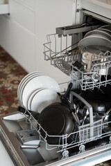 Dishwasher rack full of dirty dishes, plates, frying pan, and cutlery, ready for a wash cycle in a modern kitchen, illustrating efficiency and daily household chores