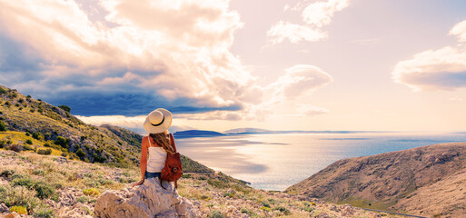 hiker woman sitting on cliff enjoying amazing panoramic view of hillside and sea © M.studio