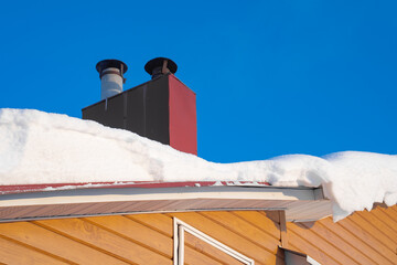 snow drifts on the roof of the house, dangerously overhanging boulders, snow removal with a shovel
