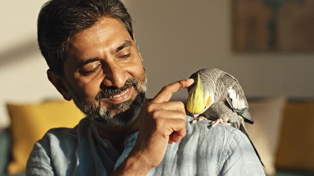 Front view of a mature man gently petting a parrot