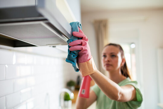 Woman cleaning kitchen range hood at home