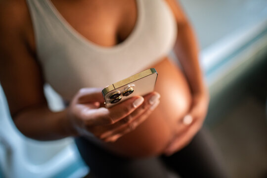 Pregnant woman using smartphone at home