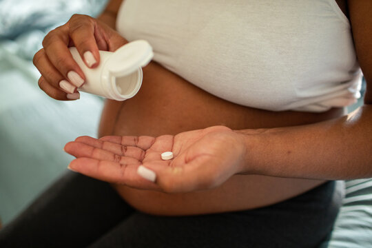 Pregnant woman taking prenatal vitamin at home