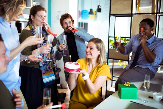 Coworkers celebrating birthday with cake in modern office
