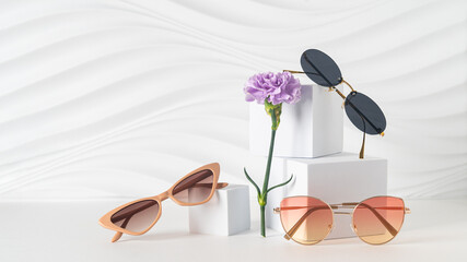 Trendy sunglasses in plastic and metallic frames on white background with flowers. Sunglasses...