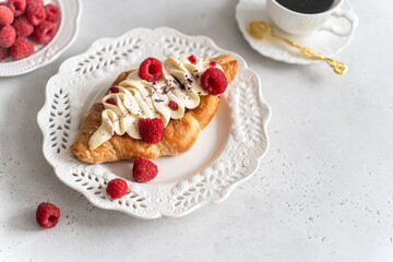 Trendy flat croissant on white plate, coffee. Delicious buttery thin croissant with fresh raspberry, cream. french breakfast. Viral Crusty flat croissant recipe, bakery, cafe menu cookbook copy space