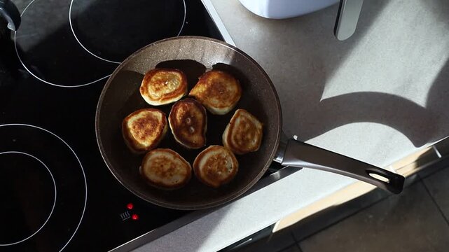 Fresh homemade pancakes frying in a hot pan. Close-up view of golden batter cooking and bubbling in oil, traditional breakfast preparation and cozy homemade food concept.