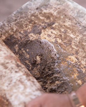 Preparing Mexican black recado on a traditional metate in the Yucatan Peninsula. A paste of spices and chilies used in Yucatecan cuisine.