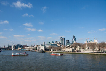 Naklejka premium London skyline view from River Thames.Panoramic view of the City of London with tourist boats and modern skyscrapers under a blue sky. Historic and modern architecture in the UK capital.