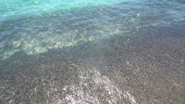 Close view of rippling sea water and small wave breaking on beach sand. Bright, clean coastal scene ideal for nature, travel, and relaxation concepts.