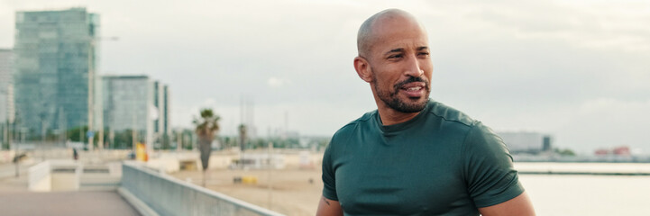 Stretching routine outdoors, yong fit man works out by the sea. Panoramic