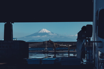 静岡県焼津市の小川漁港のシルエットと建物の間から望む冬の富士山
