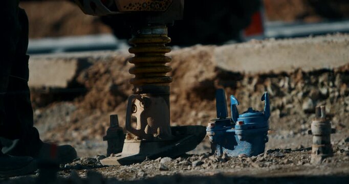 Vibratory rammer compacting soil at a construction site